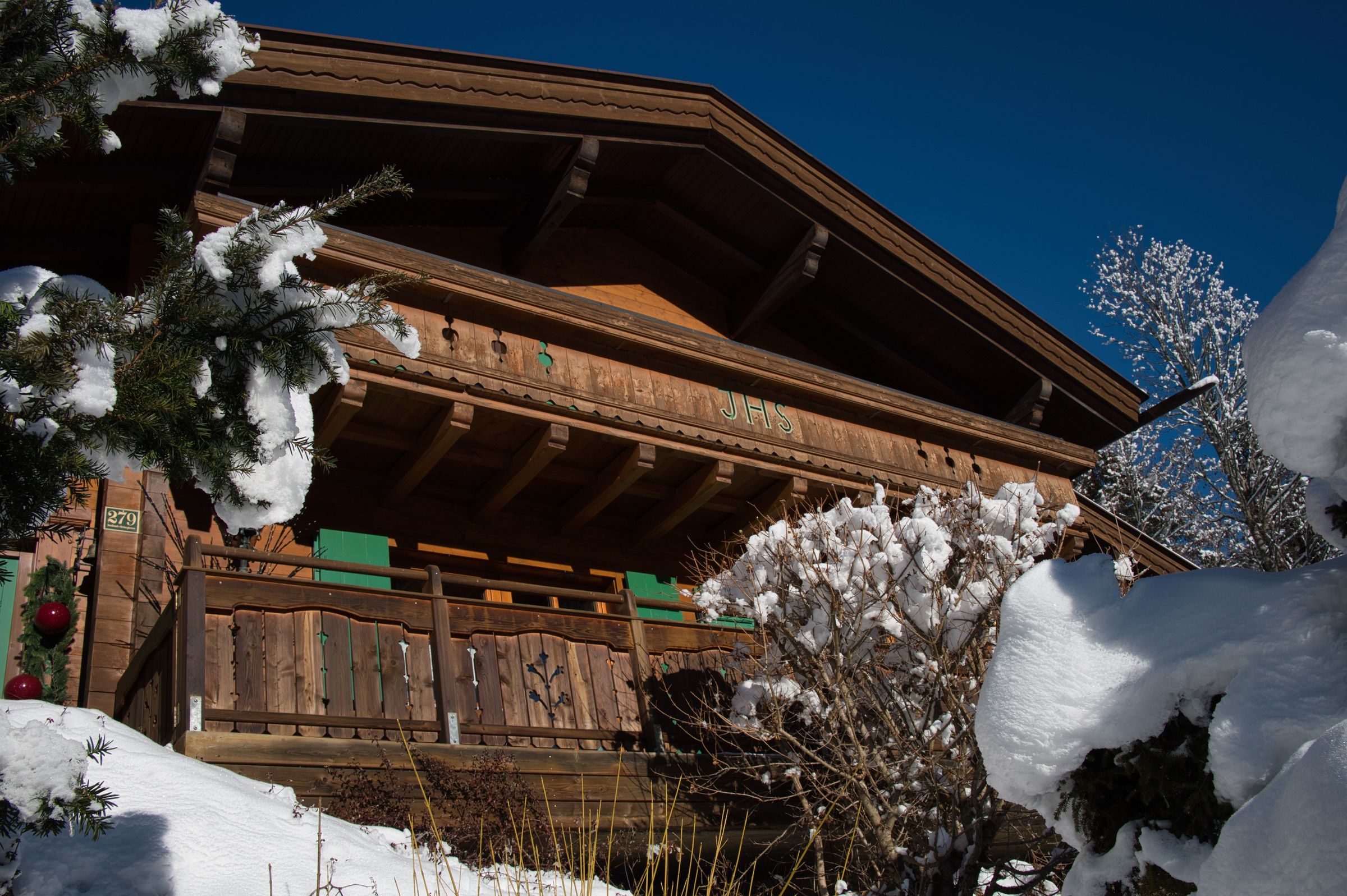 Chalet Glemm Alpin im Winter mit verschneiten Bäumen vor blauem Himmel