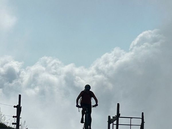 Mountainbiker als Silhouette vor Wolken
